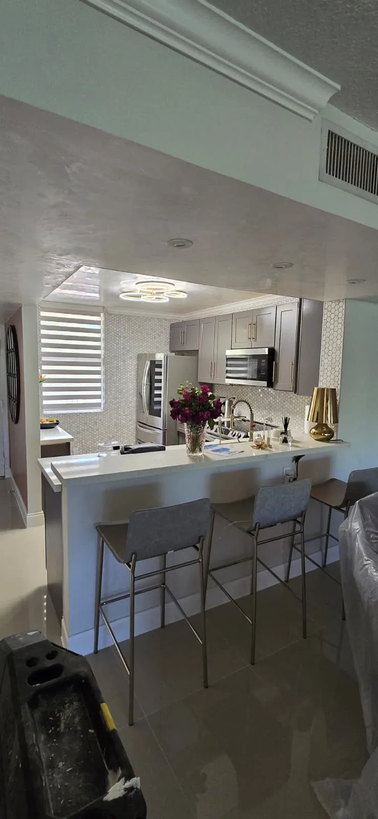 Gray shaker kitchen with white quartz peninsula and bar stools